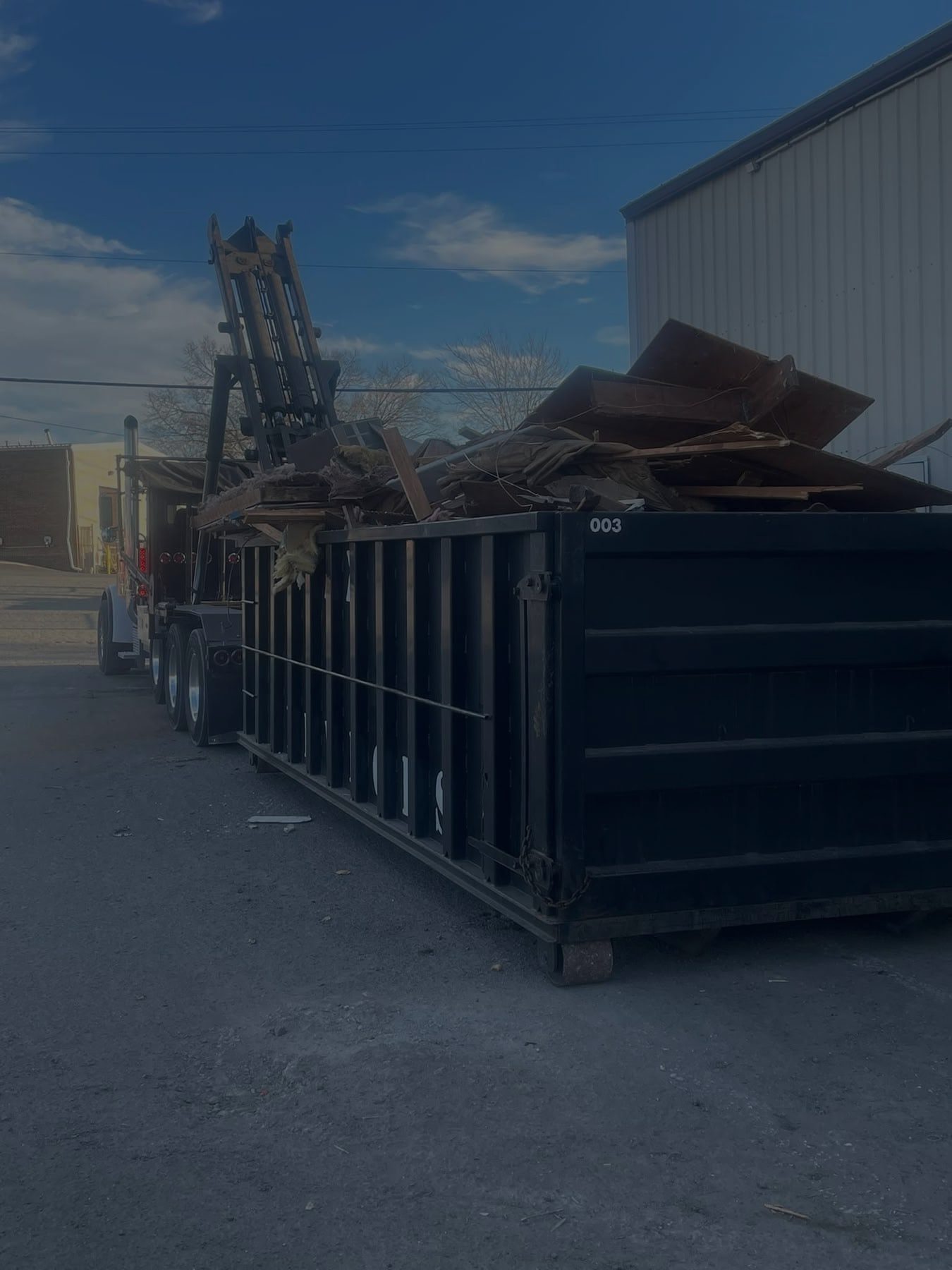 Dump truck unloading construction debris into container.