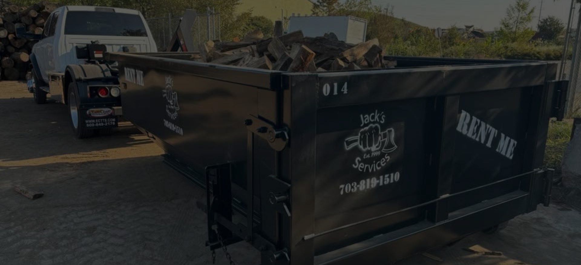 Black dumpster truck with wood debris.